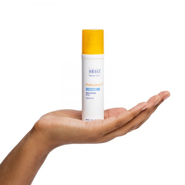 A person holding onto a bottle of sunscreen